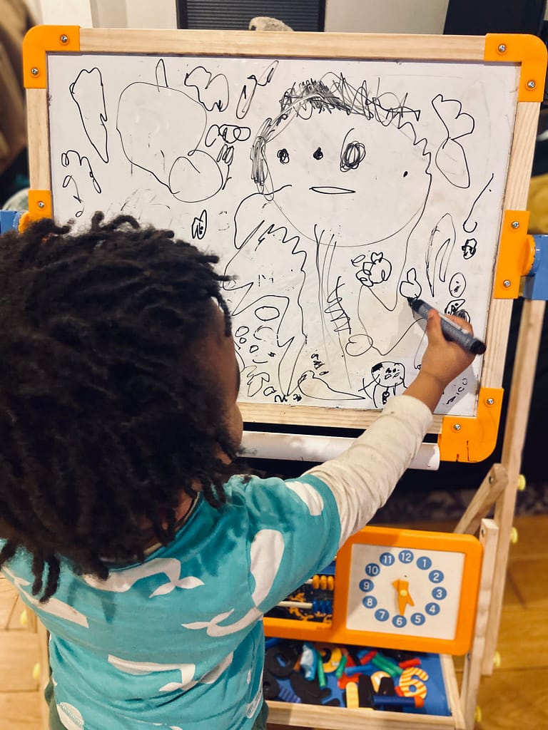 a child writing on a whiteboard, independence and growing up learning how to write adn draw