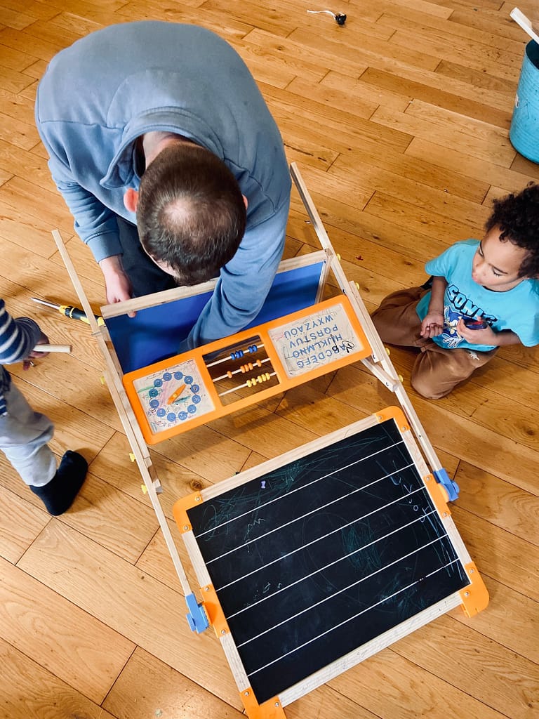 "it takes a village" to raise a child, a father and his sons building a whiteboard and fixing it