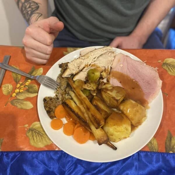 A traditional Christmas dinner with turkey, ham, stuffing, roast potatoes, carrots, Brussels sprouts, and gravy